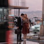 smiling man in suit and woman in skirt in city