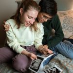 couple sitting on a bed looking at ultrasound photos