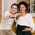 man and pregnant woman watching television