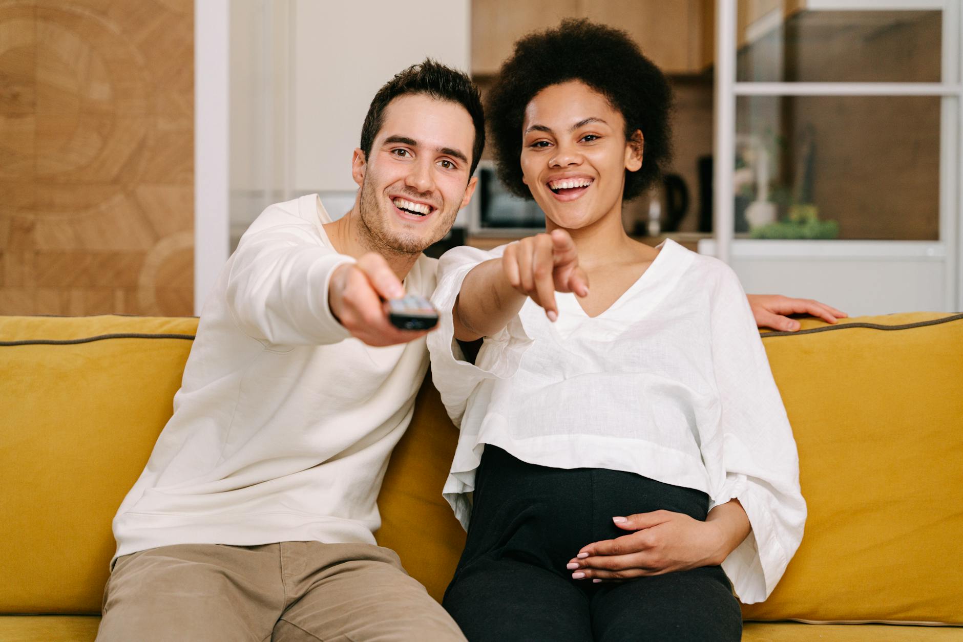 man and pregnant woman watching television
