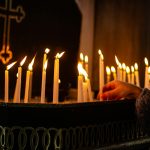 person putting candle in church