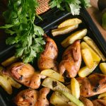 cooked chicken with potatoes on black metal tray