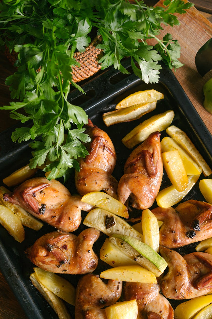cooked chicken with potatoes on black metal tray
