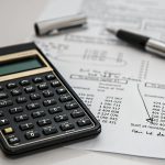 black calculator near ballpoint pen on white printed paper
