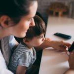 a woman and child looking at a cell phone