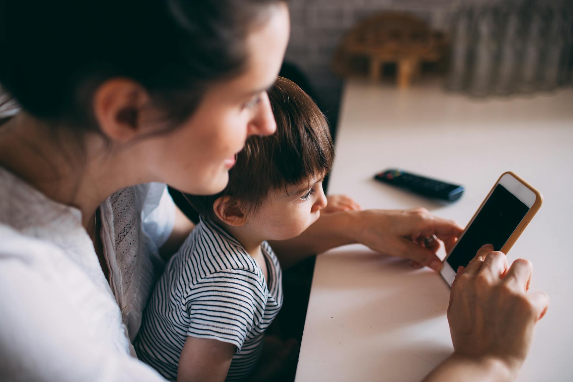 a woman and child looking at a cell phone