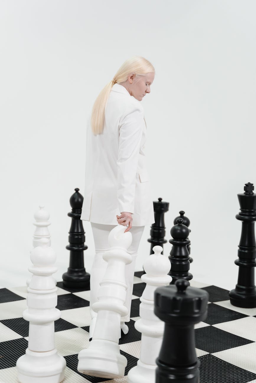 a woman in a white outfit playing chess on a giant chessboard