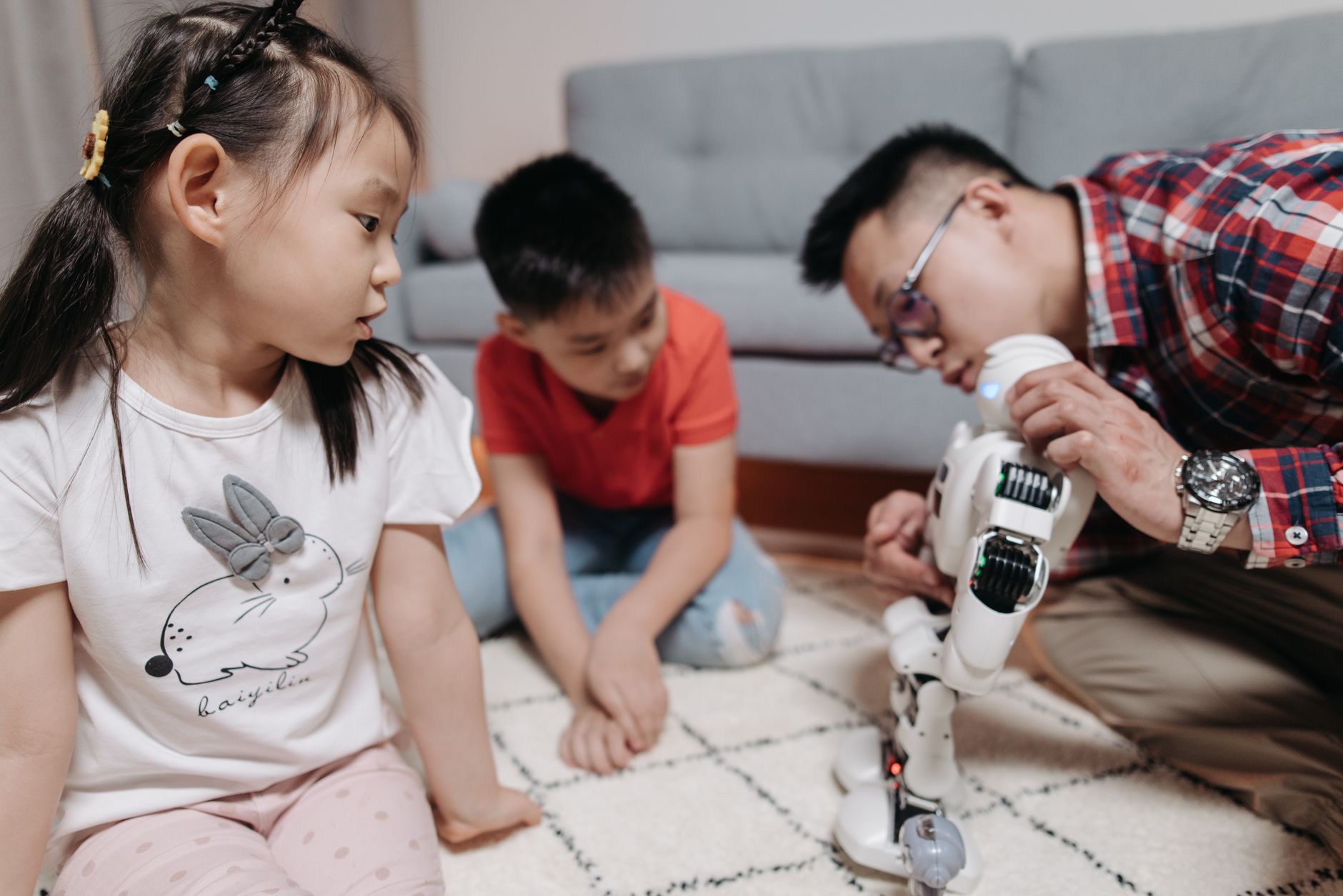 father controlling the white robot he is holding in front of his kids